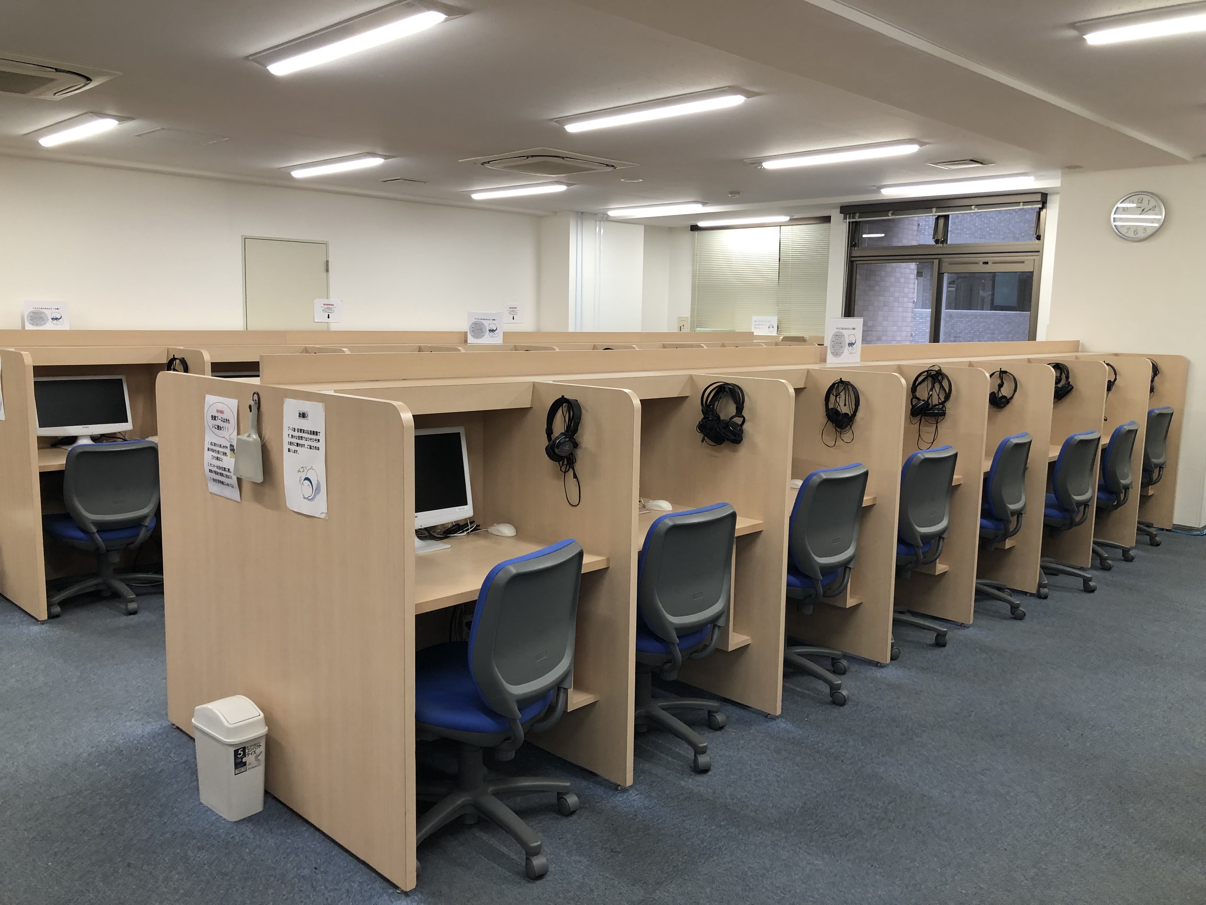 受講ブース室（68台のPCとヘッドフォンに加えて、広々としたお部屋で受講に集中できる環境が整っています。）